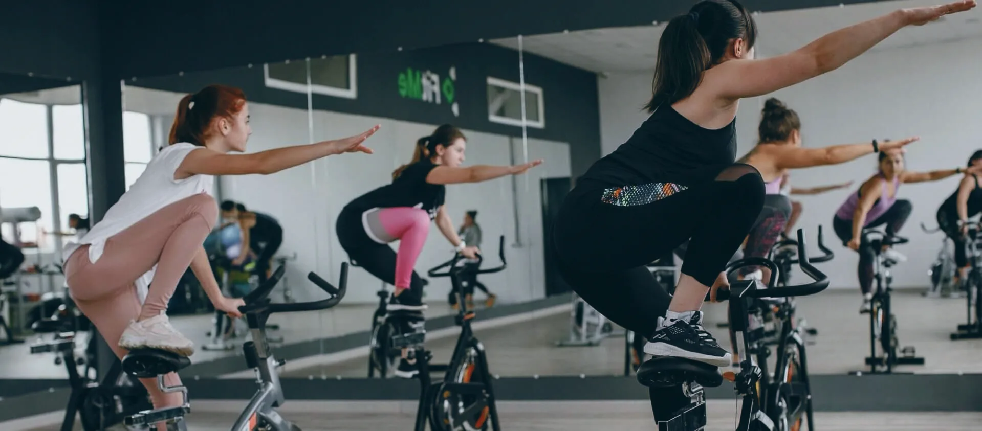 Груповий клас на спін-байках у залі FitMe — учасниці в русі перед дзеркалами